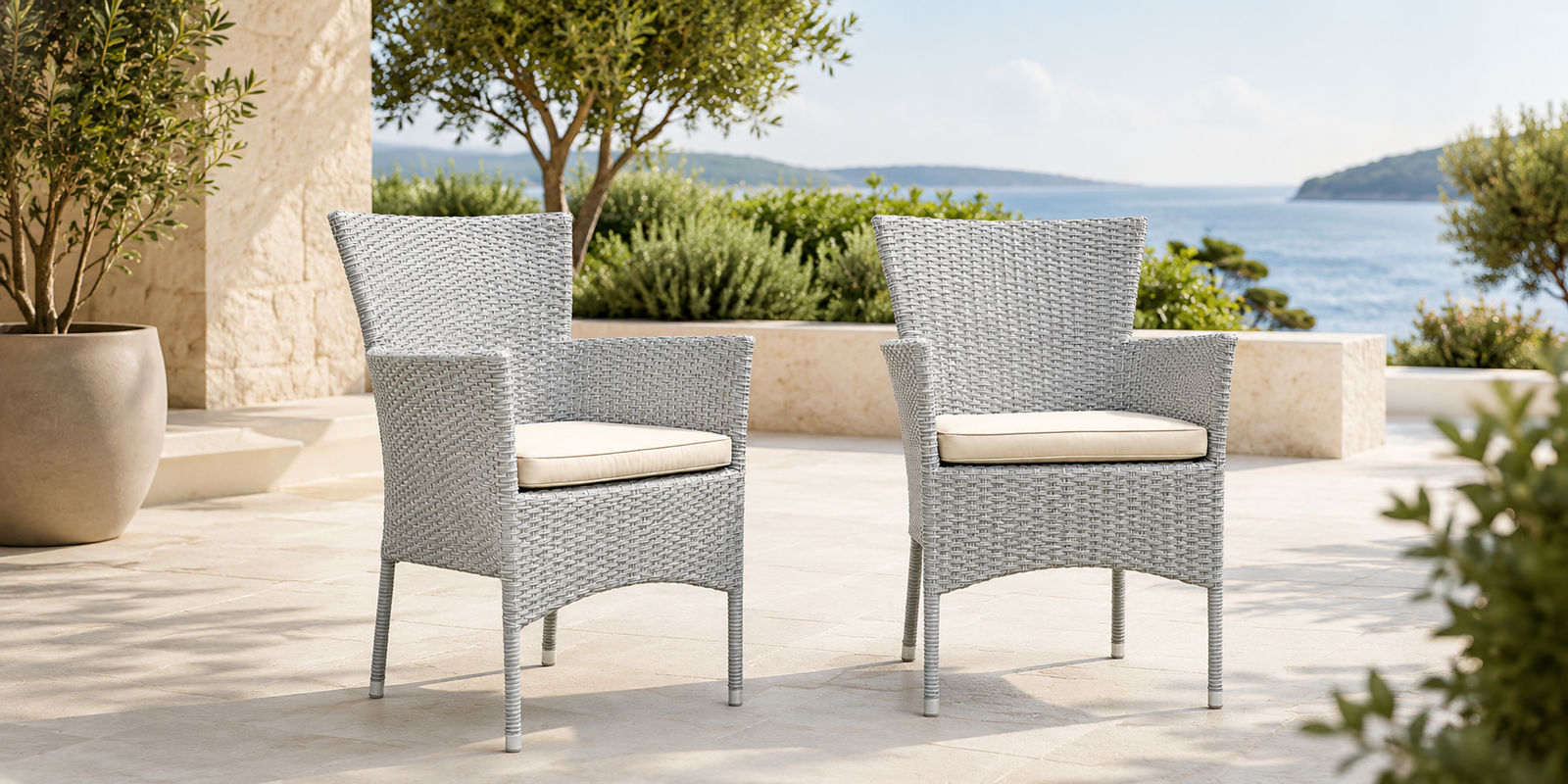 Two wicker chairs with beige cushions on a patio overlooking a scenic ocean view Two wicker chairs with beige cushions on a patio overlooking a scenic ocean view